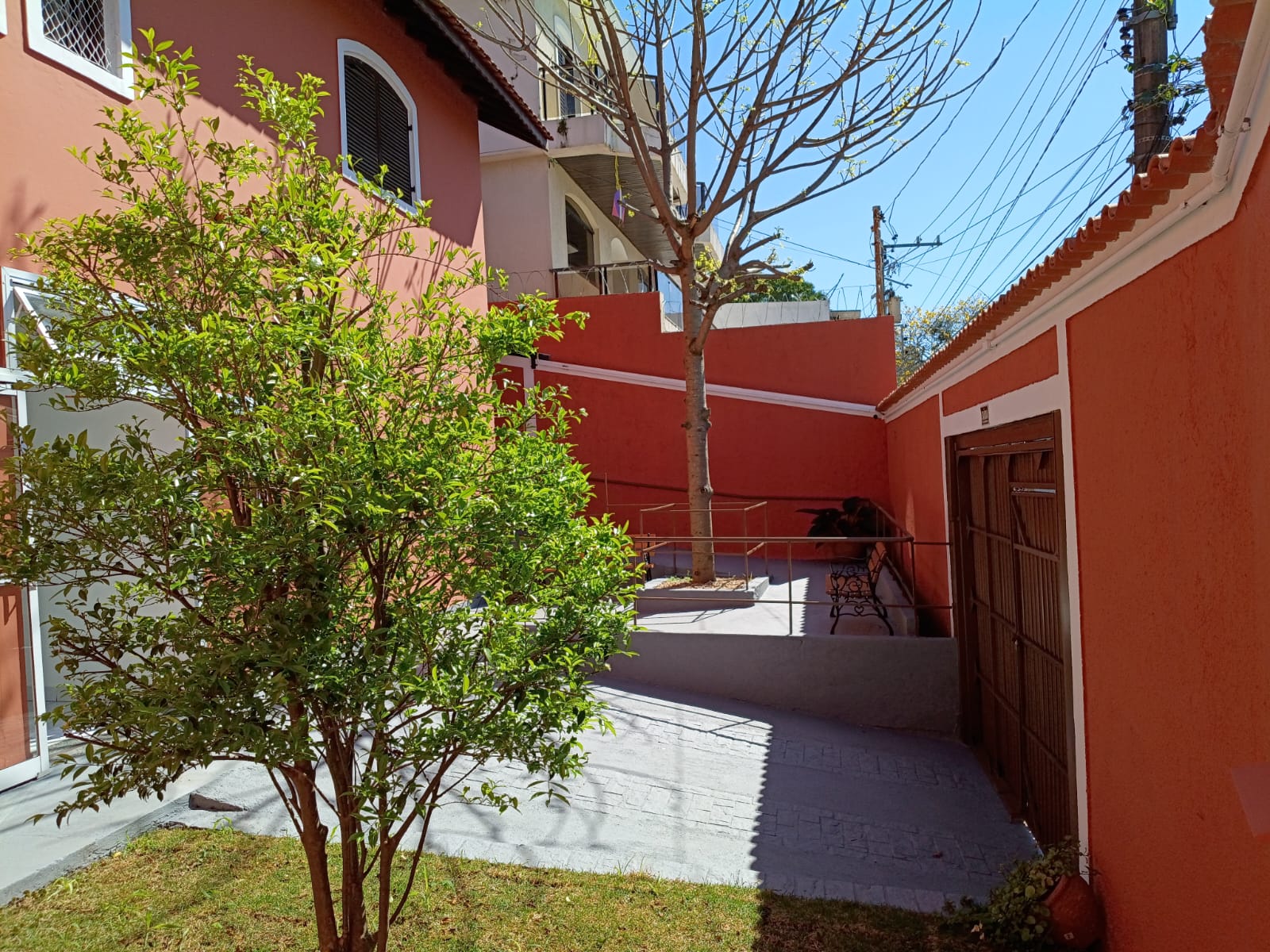 Jardim interno da GERAS com árvore, rampa e banco