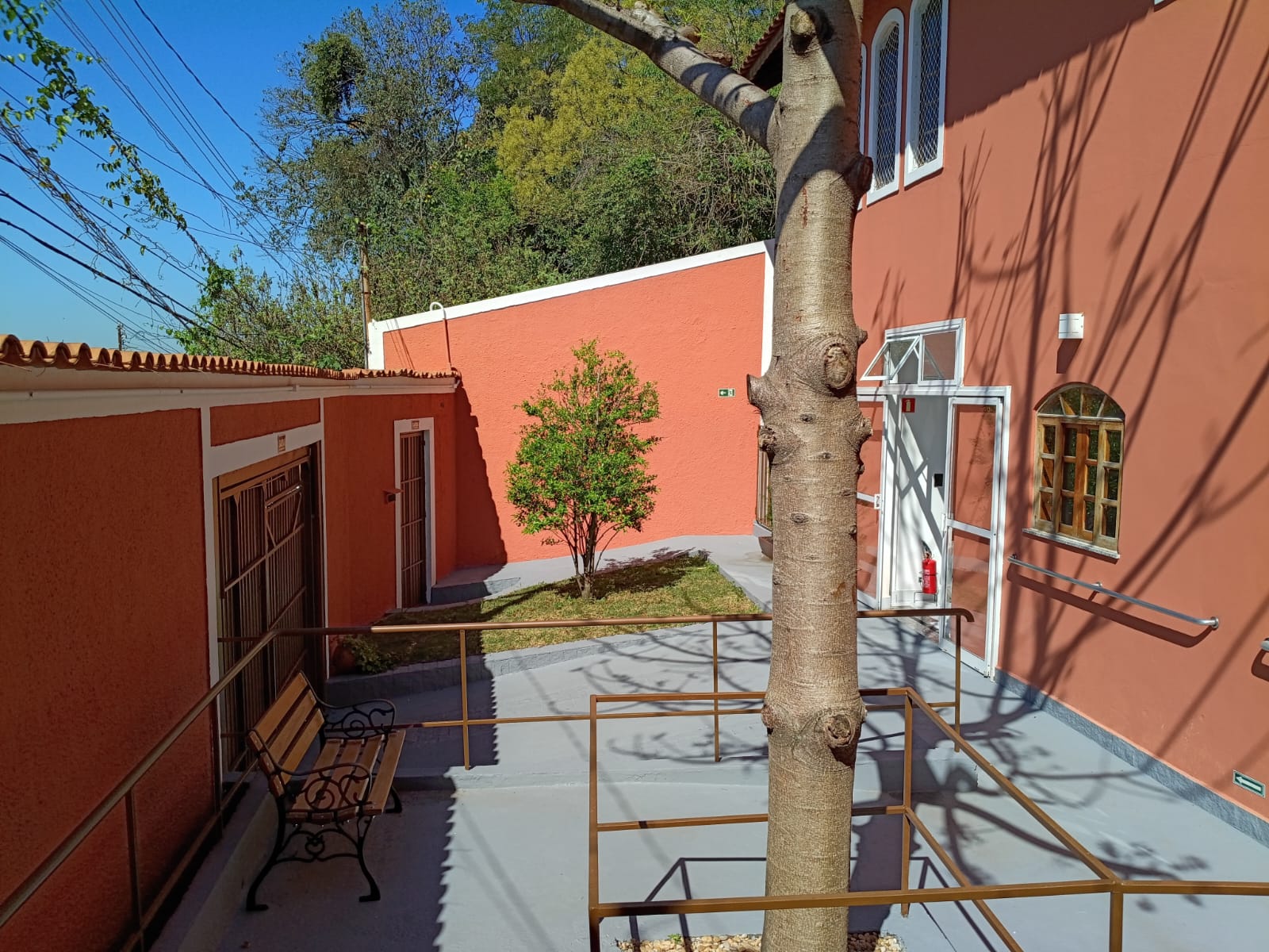 Pátio arborizado com bancos e caminhos acessíveis