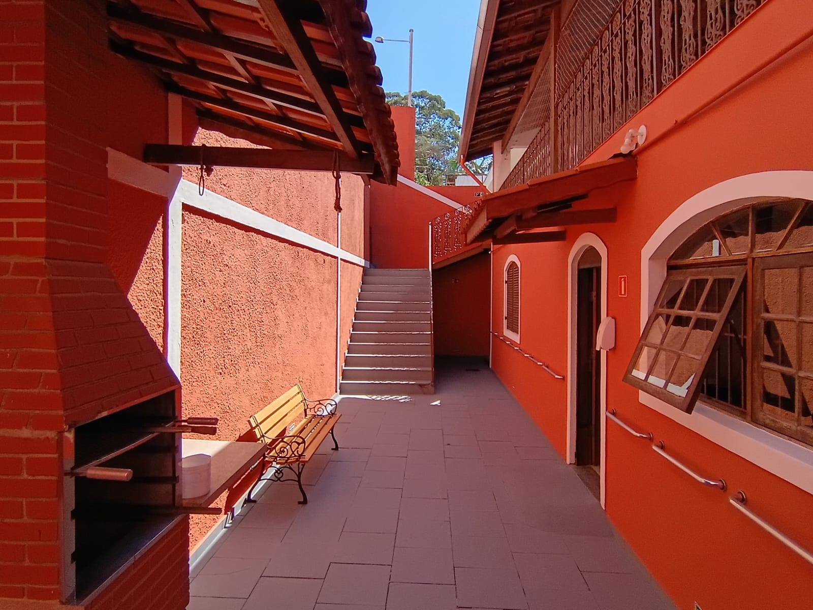 Pátio ensolarado da GERAS com churrasqueira e banco