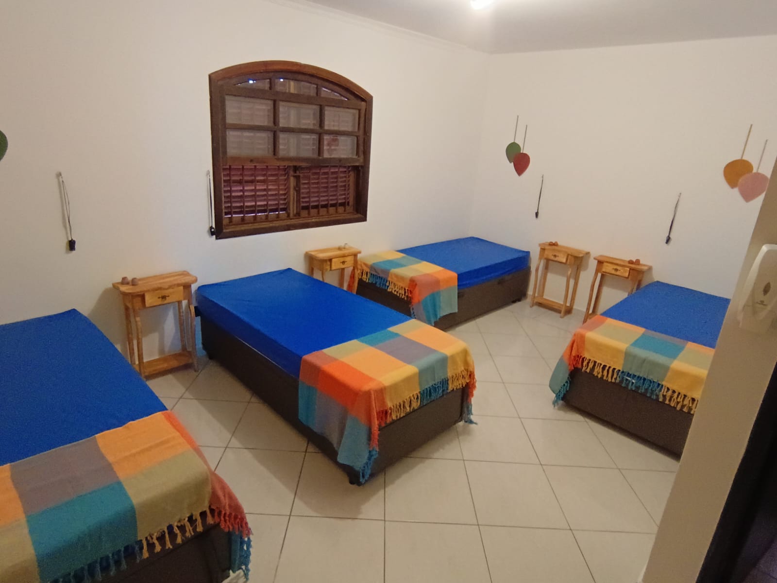Quarto compartilhado com quatro camas e mesas de apoio