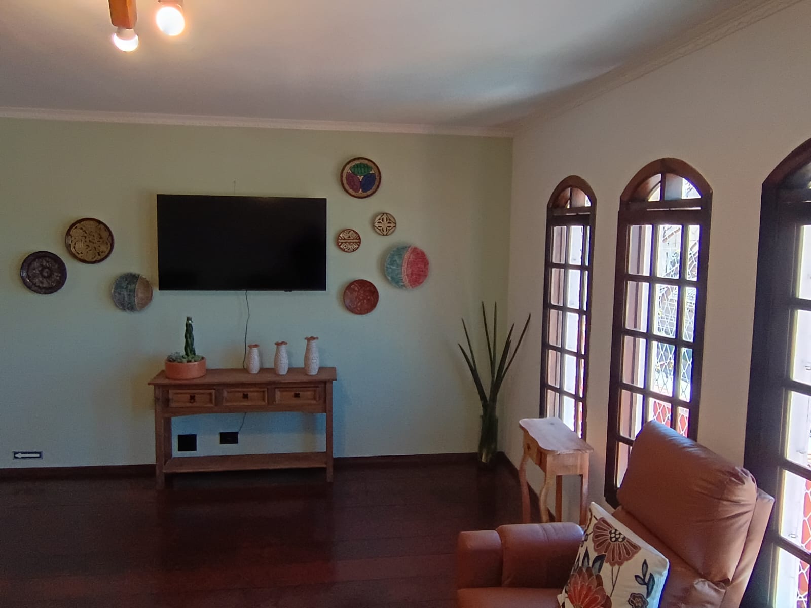 Sala de TV acolhedora com poltrona e janelas amplas